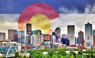 Colorado flag behind Denver skyline: Denver recently passed a new law that requires facilities that use insert gas to install oxygen deficiency monitors wherever these gases are used in excess of 100 pounds.
