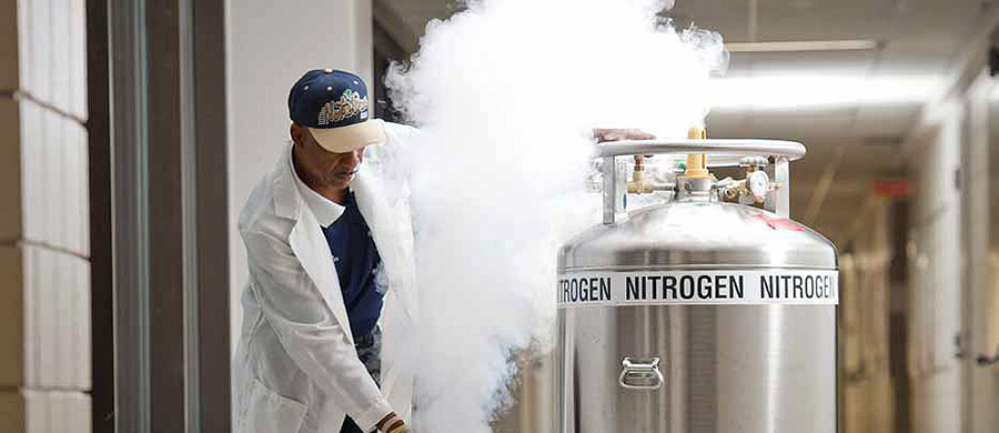 Man pushing nitrogen tank through university laboratory: An explosion at a university research lab in Hawaii last year highlights the dangers of working with compressed gas and the need for safety equipment on campus.